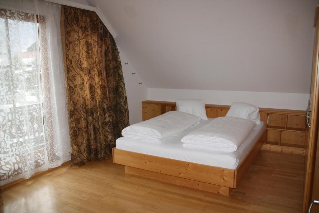 Bett in einem Zimmer mit einem großen Fenster in der Unterkunft Haus Johannes in Maishofen