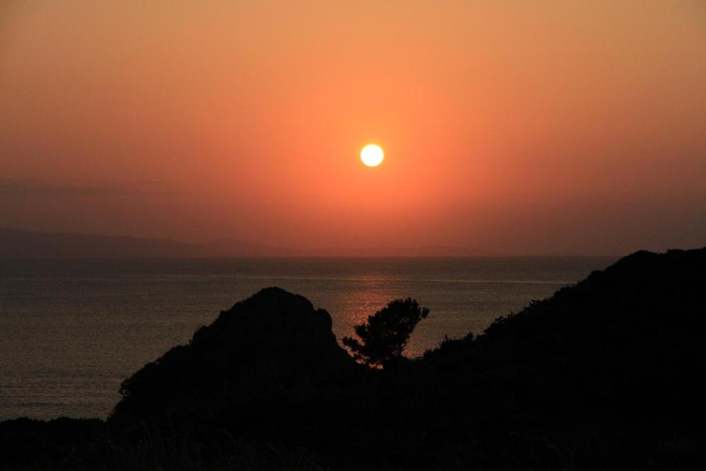a sunset over the ocean with the sun in the sky at Joya in Ishigaki Island