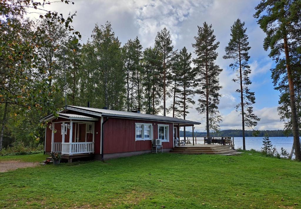 a small red cabin with a porch and a deck at Holiday Home Joutsen in Parikkala