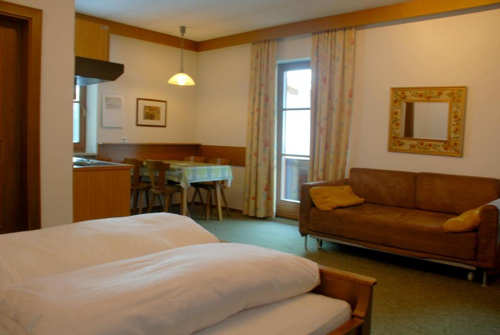 Pokój hotelowy z łóżkiem, kanapą i stołem w obiekcie Residence Schneiderhof w mieście San Candido