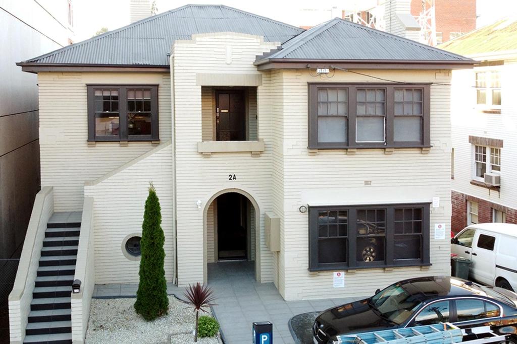 3 Bedroom 2 Bathroom Heathfield Avenue Salamanca 50m في هوبارت: بيت أبيض مع سيارة متوقفة أمامه