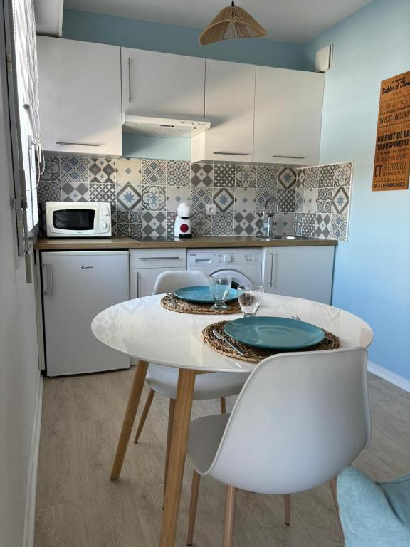 - une cuisine avec une table blanche et des chaises blanches dans l'établissement Studio proche plage et commerces, à Les Sables-dʼOlonne