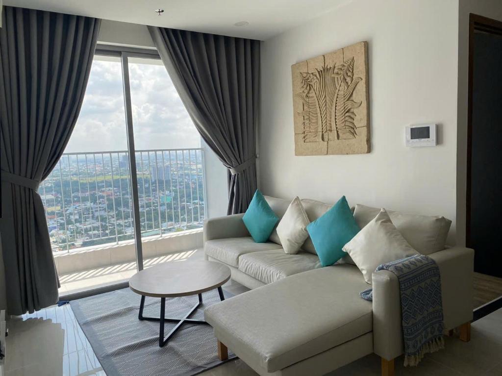 a living room with a couch and a large window at Happy One Central - Binh Duong in Phú Lợi