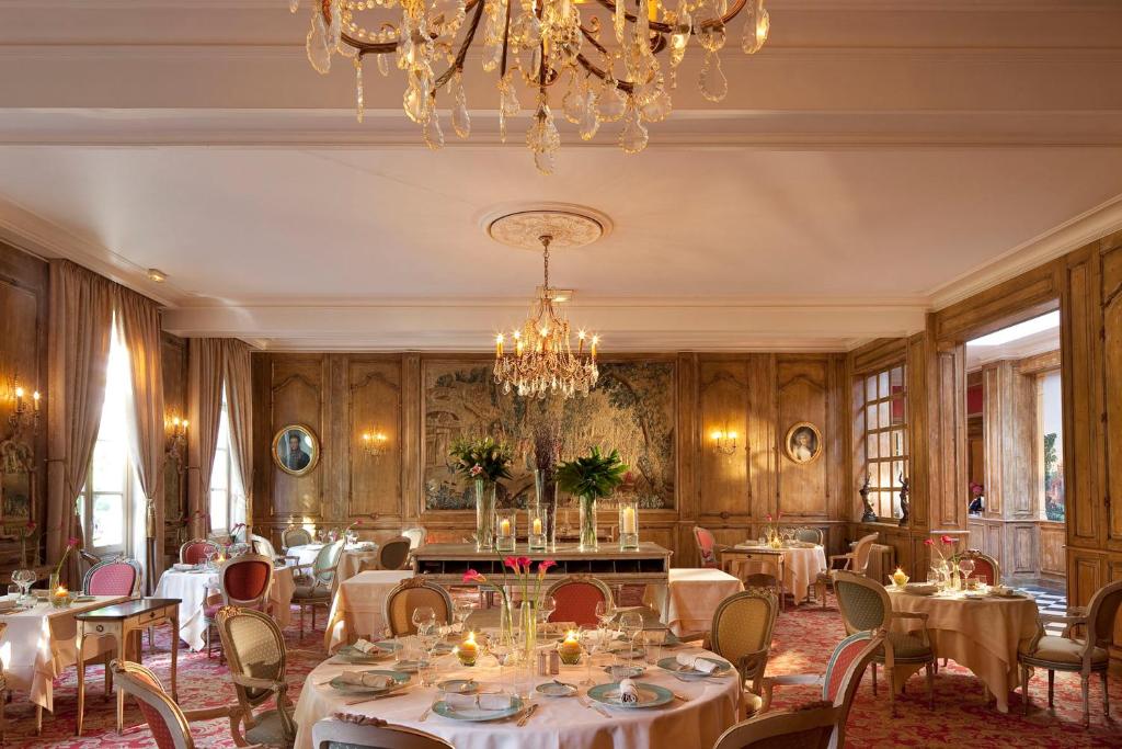 une salle à manger avec des tables et des chaises ainsi qu'un lustre dans l'établissement La Chartreuse Du Val Saint Esprit, à Gosnay