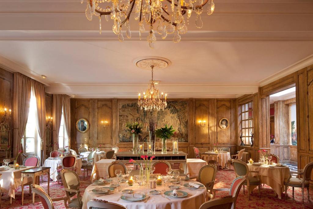 a dining room with tables and chairs and a chandelier at La Chartreuse Du Val Saint Esprit in Gosnay