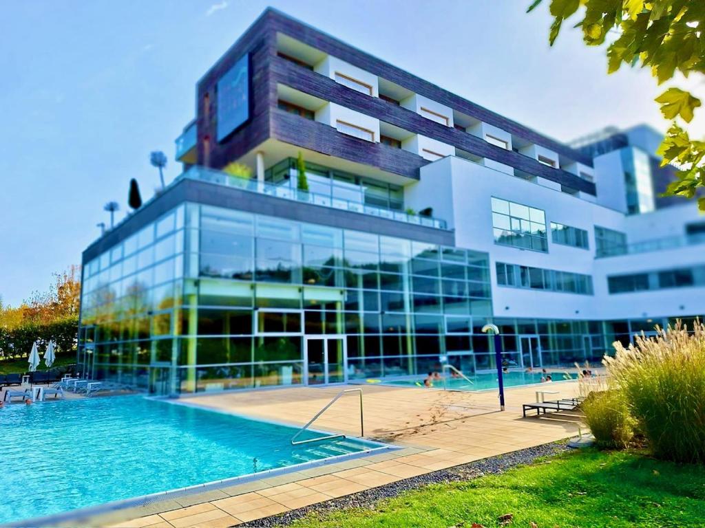 バート・ヴァルタースドルフにあるWHIRLPOOL-SUITE AMADEUS - Weitblick - Golf & Wellness - direkter Bademantelgang - ADULTS ONLYの大きな建物で、目の前にスイミングプールがあります。