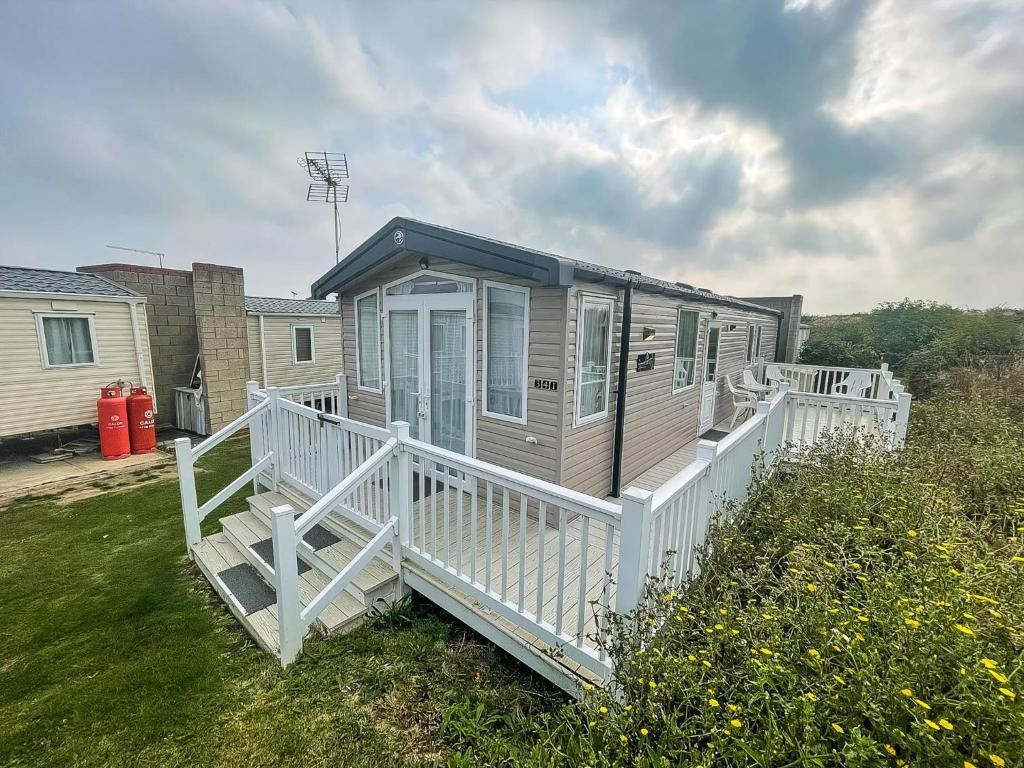 a mobile home with a porch and a white railing at Beautiful Caravan With Decking At Naze Marine Park, Sleeps 8 Ref 17341Br in Walton-on-the-Naze