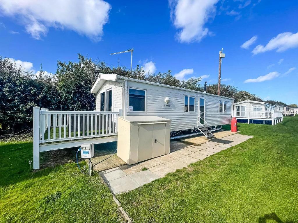 a mobile home in a yard with a white fence at Lovely Dog Friendly Caravan For Hire At California Cliffs, Norfolk Ref 50027K in Great Yarmouth