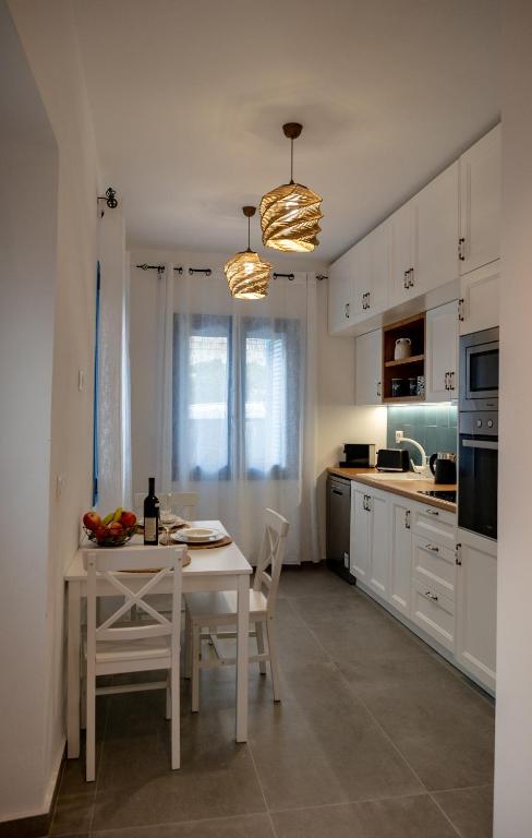 a white kitchen with a white table and chairs at Diolanth traditional house in Koskinou