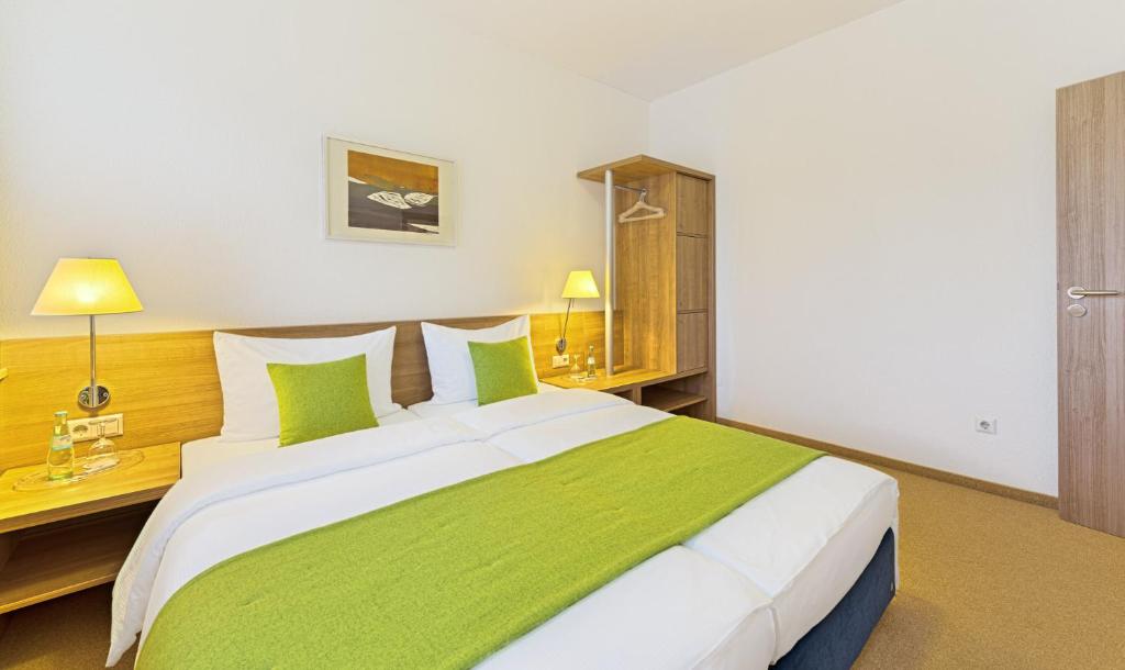 a bedroom with a large white bed with green pillows at Sapia Hotel St. Fridolin in Bad Säckingen