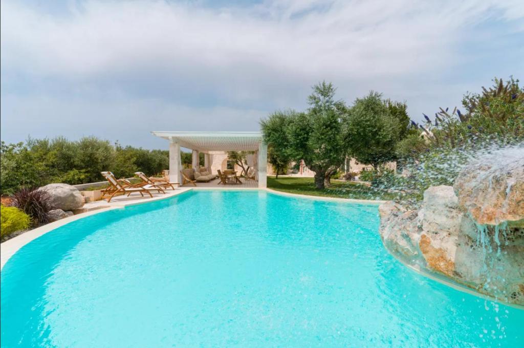 a swimming pool with a water fountain in a yard at PETRA ANTIQUA in Locorotondo