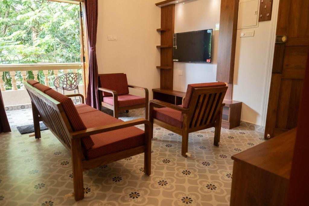 a living room with chairs and a tv and a table at Vistar Holidays in Goa