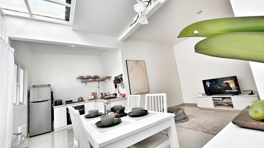 a kitchen with a white table and a refrigerator at Villa LA Mansion Lembang - 2BR for 2-6 Guest stay in Lembang