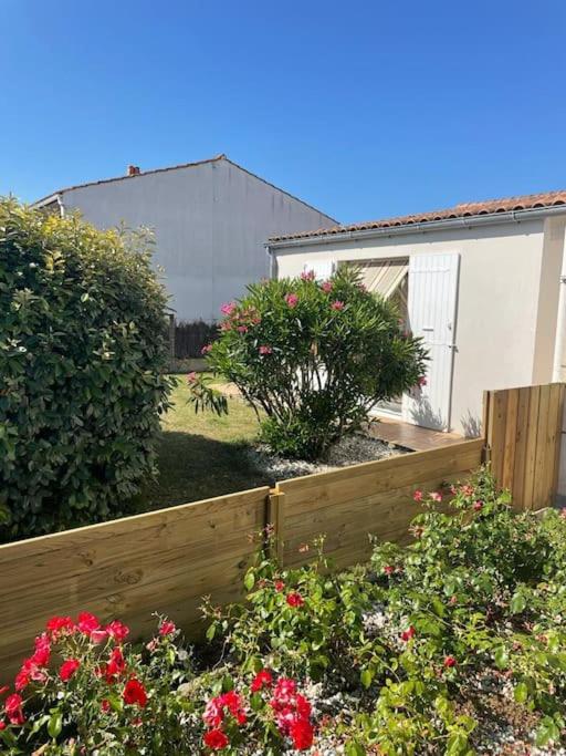 une clôture en bois devant une cour fleurie dans l'établissement Maison Mosse, à Angoulins-sur-Mer