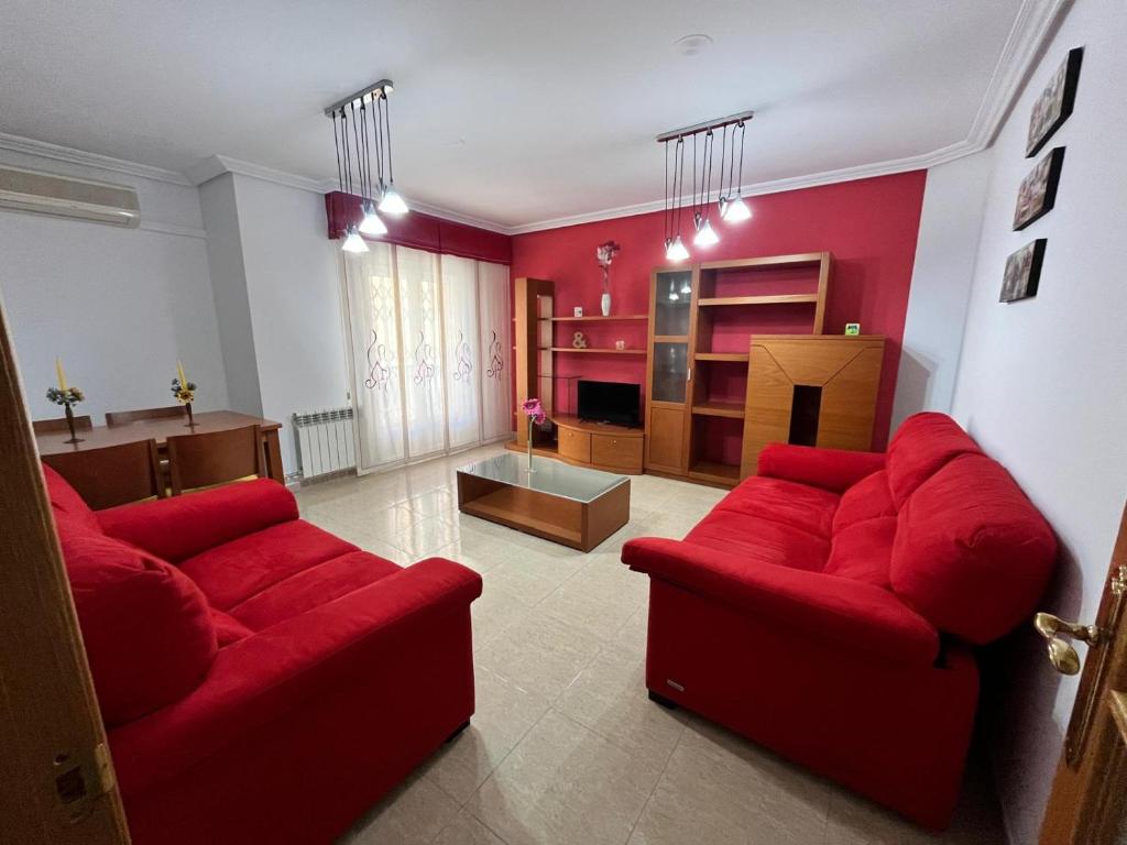 Una sala de estar con un sofá rojo y una mesa. en Alojamiento MB Baza, en Baza
