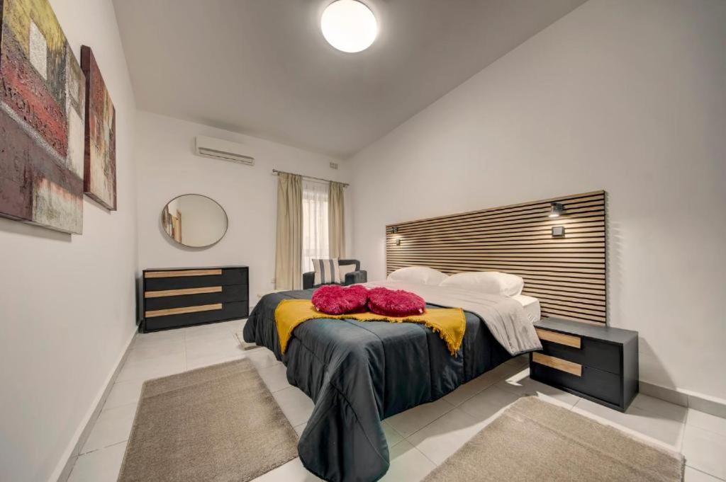 a bedroom with a bed with two red pillows on it at Rachel's Apartment in Paceville