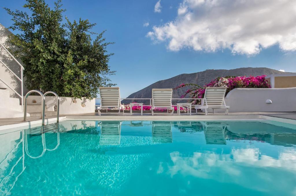 una piscina con sillas y vistas a la montaña en White Cave Private Villa, en Pirgos