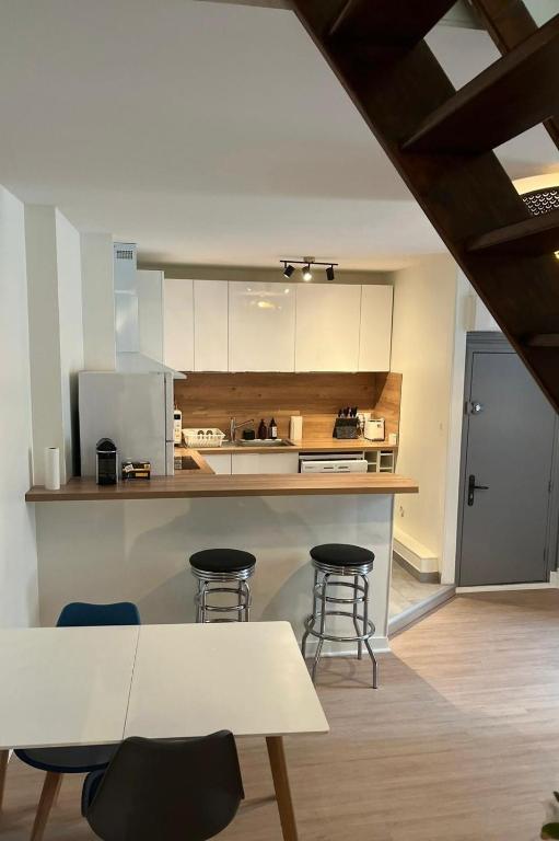 une cuisine avec un comptoir et des tabourets dans une pièce dans l'établissement Halle aux Blés- Appartement au Centre Historique, à Bourges
