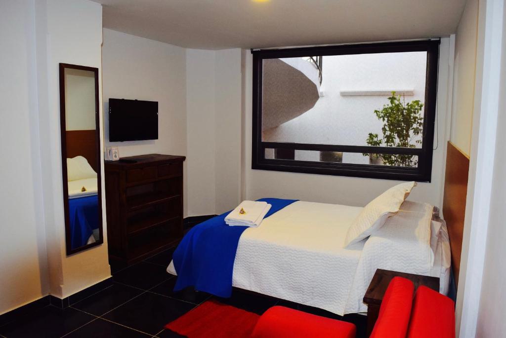 a bedroom with a bed and a window and red chairs at Camino A La Villa Cucaita Hotel in Cucaita