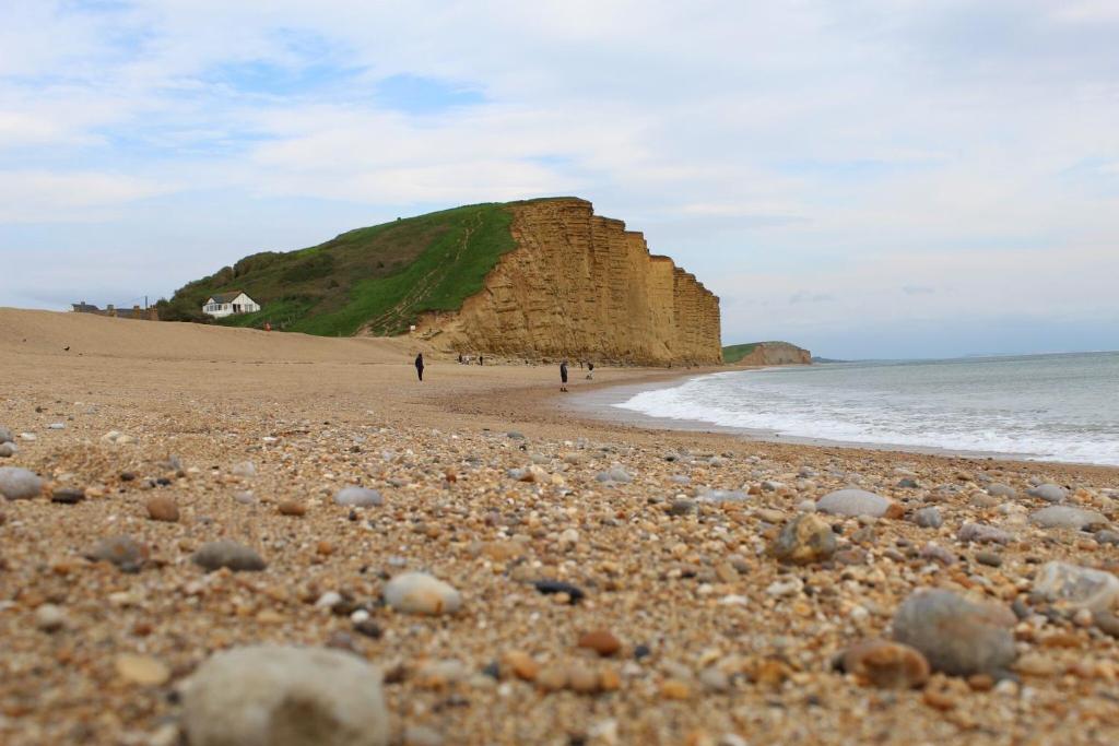 a rocky beach with people walking on the beach at Bridport Arms Hotel in West Bay