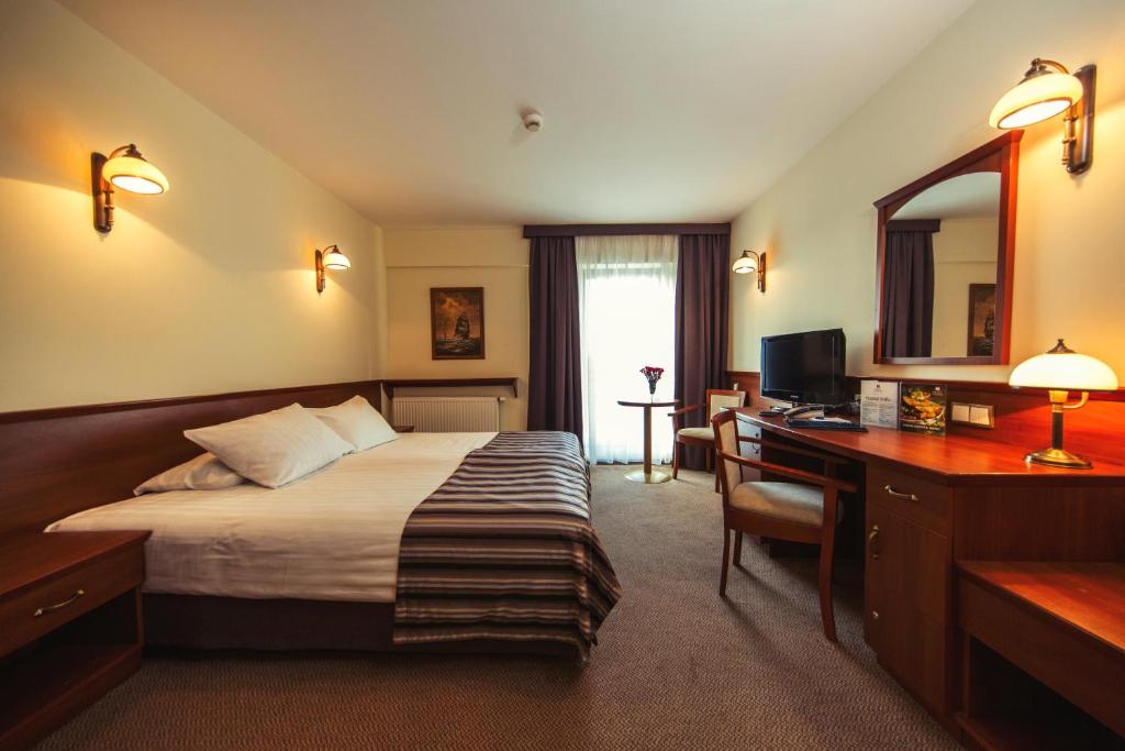 a hotel room with a bed and a desk with a computer at Hotel Great Polonia Conrad Kraków in Kraków