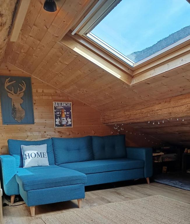 - un canapé bleu dans une chambre avec une lucarne dans l'établissement Appartement mansardé cocooning, à Saint-Martin-Vésubie