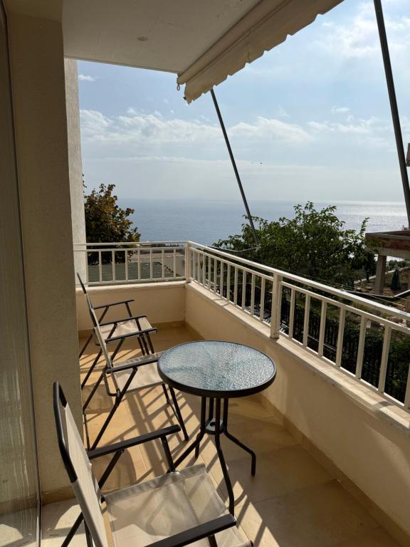 a balcony with a table and chairs and the ocean at Natali Apartments in Gjilek