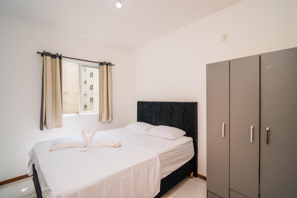 a white bedroom with a bed and a cabinet at Rental São José - Acomodações Residenciais II in São José