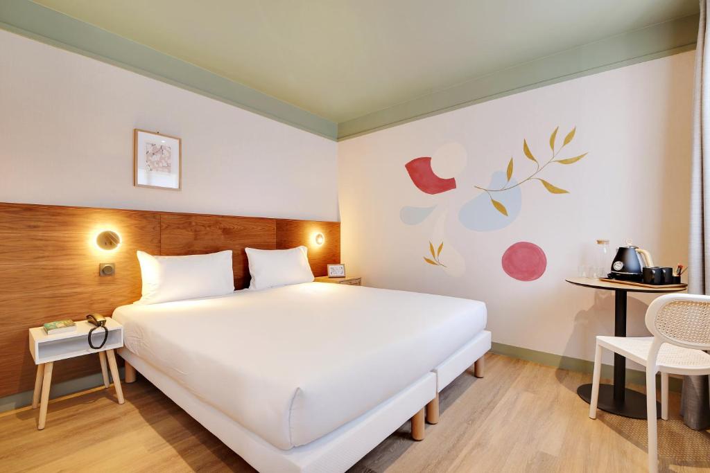 Un dormitorio con una gran cama blanca y una mesa. en Hôtel Cocoon, en Saint-Ouen