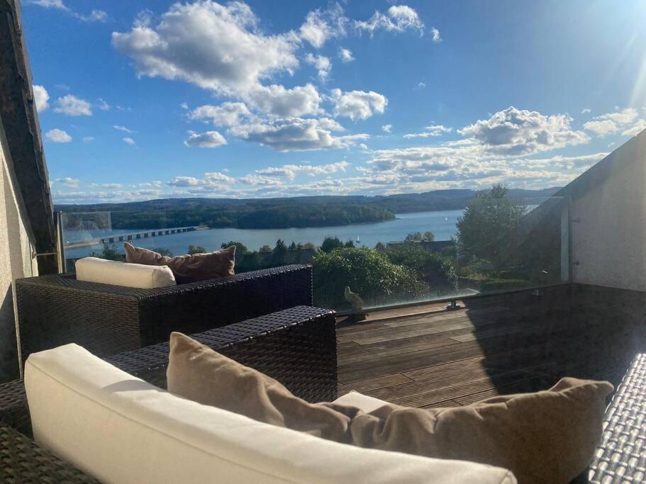 een balkon met een bank en uitzicht op een meer bij Villa Kaja mit Pool, Kamin und traumhaftem Blick auf den Möhnesee in Delecke