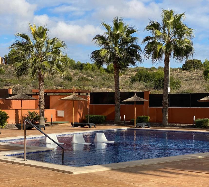 a swimming pool with palm trees in front of a building at Penthouse Palapagolf in Orihuela Costa