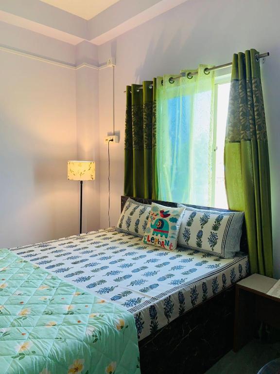 a bedroom with a bed with green curtains and a window at Windchime 9 in Guwahati