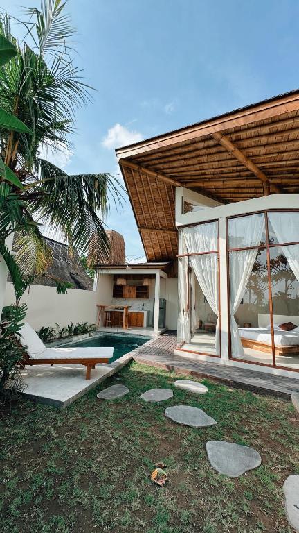 a villa with a swimming pool and a house at Capila Villa Bali in Canggu