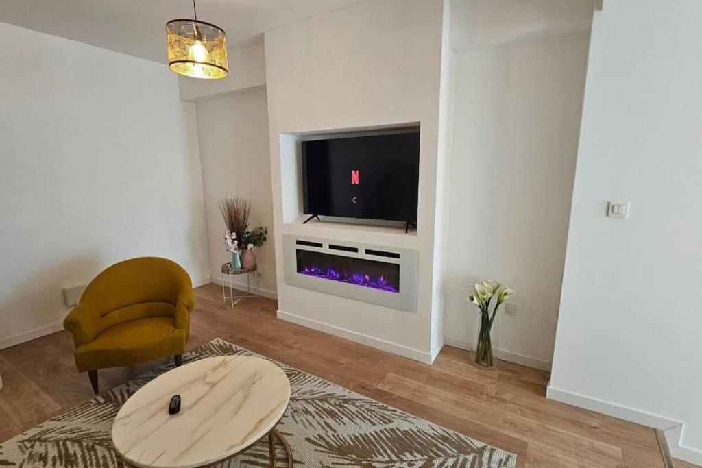 - un salon avec une télévision, une chaise et une table dans l'établissement Résidence des 4 mares, à Amfreville-la-Mi-Voie