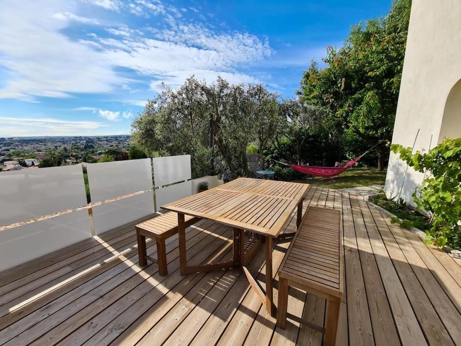 une terrasse en bois avec une table en bois et deux chaises dans l'établissement La Petite Gloriette, à Allauch