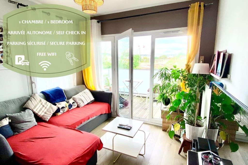 - un salon avec un canapé rouge en face d'une fenêtre dans l'établissement Appartement cosy - balcon - parking gratuit - 10min centre ville, à Cenon