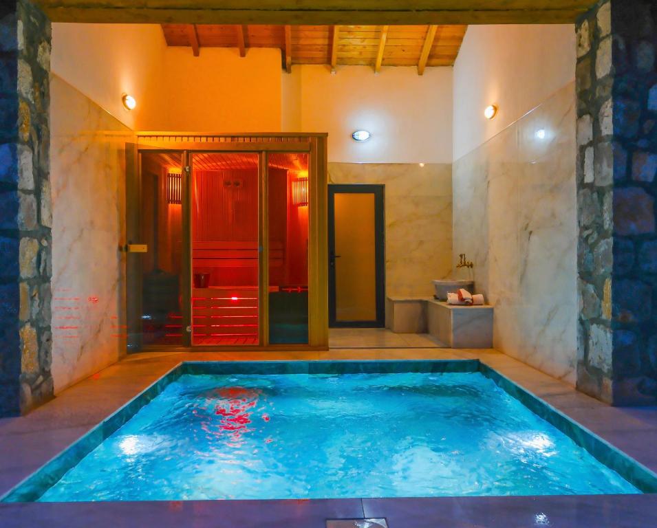 a large swimming pool in a bathroom with a shower at Luxury Stone House With Turkish Hamam, Sauna, İndoor and Outdoor Pool in Fethiye in Mugla