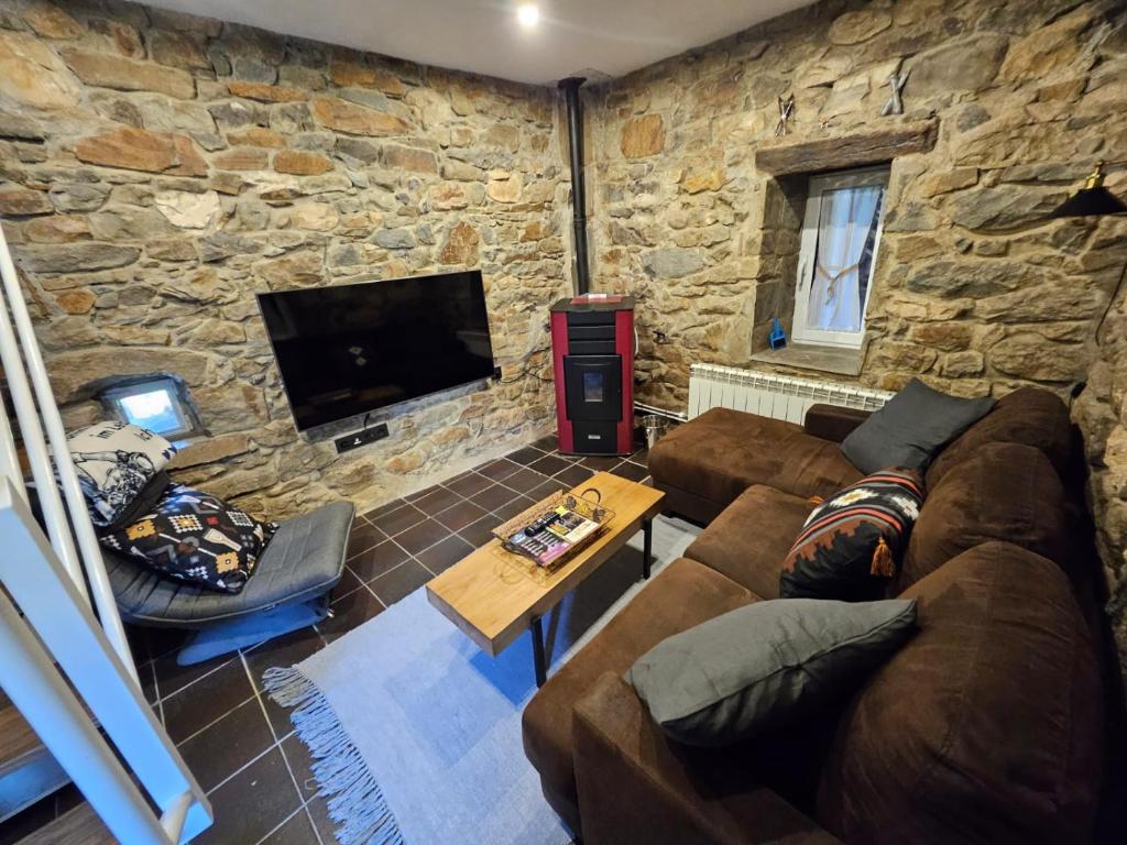 a living room with a couch and a tv at Casita con encanto, les gaites in Collanzo