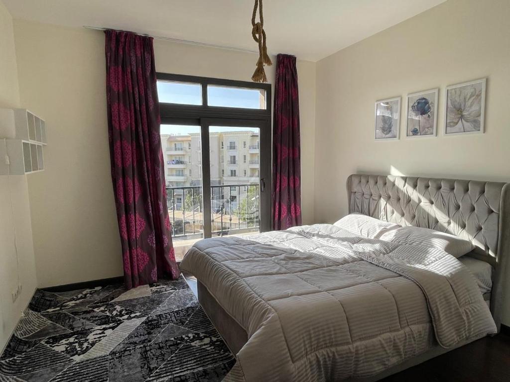 New cairoにあるMivida Coco apartmentのベッドと大きな窓のある寝室