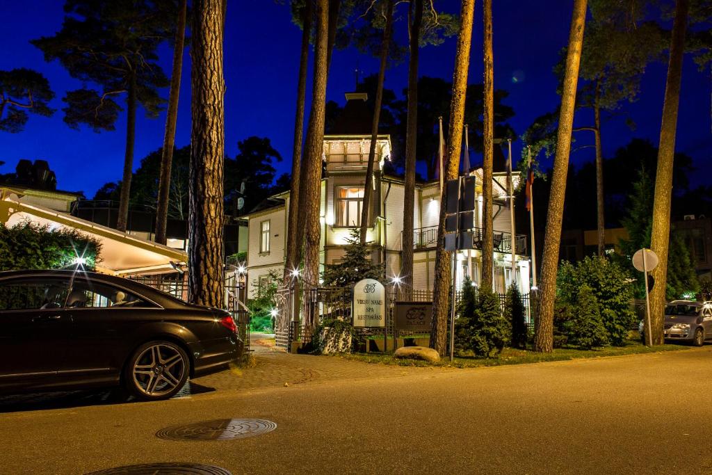 a car parked in front of a house with palm trees at TB Palace Hotel & SPA in Jūrmala