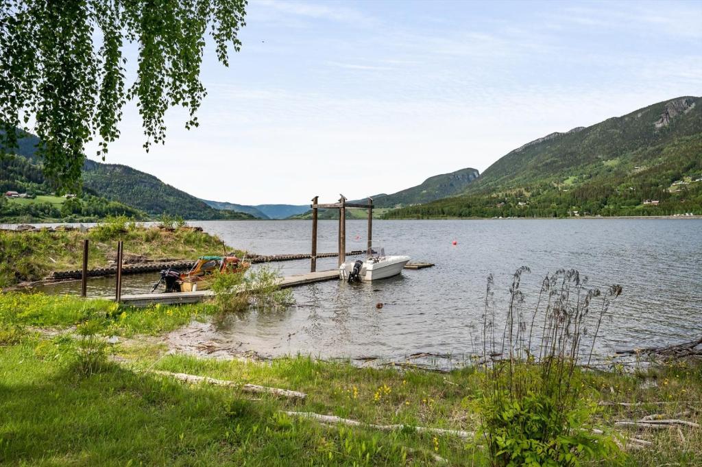 a boat is docked at a dock on a lake at Hytte med fin natur in Mork