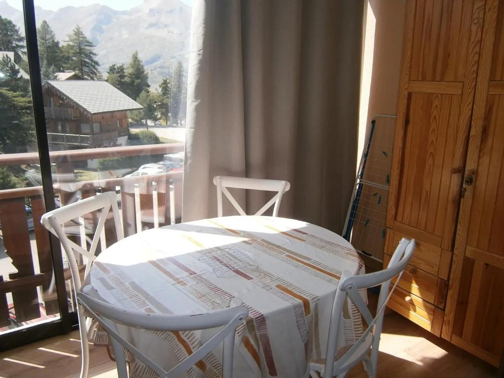 une table blanche et des chaises dans une pièce avec une fenêtre dans l'établissement Coquet studio à Le Dévoluy de 24 m², à Saint-Étienne-en-Dévoluy