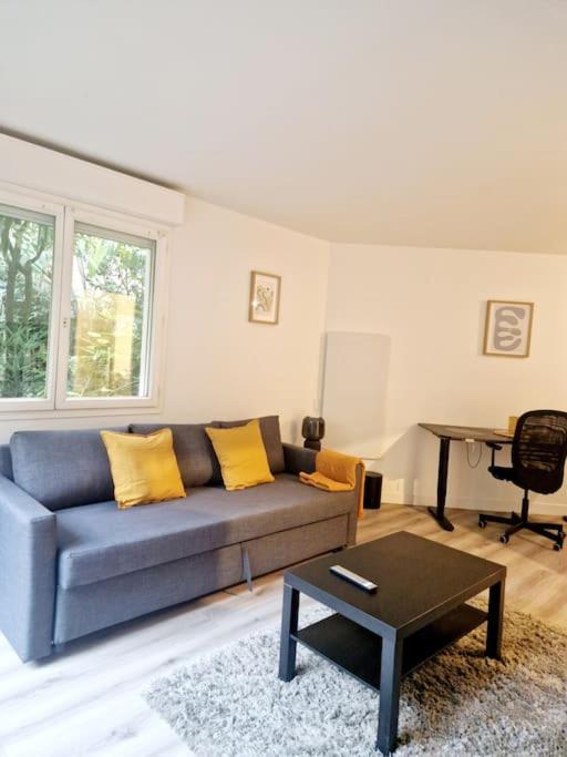 un salon avec un canapé et une table dans l'établissement Charmant Studio au Cœur de Boulogne avec jardin, à Boulogne-Billancourt