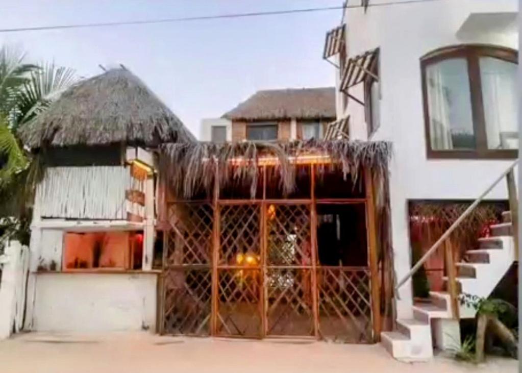a building with a thatch roof and a large door at Casa Iguana hotel boutique in El Cuyo