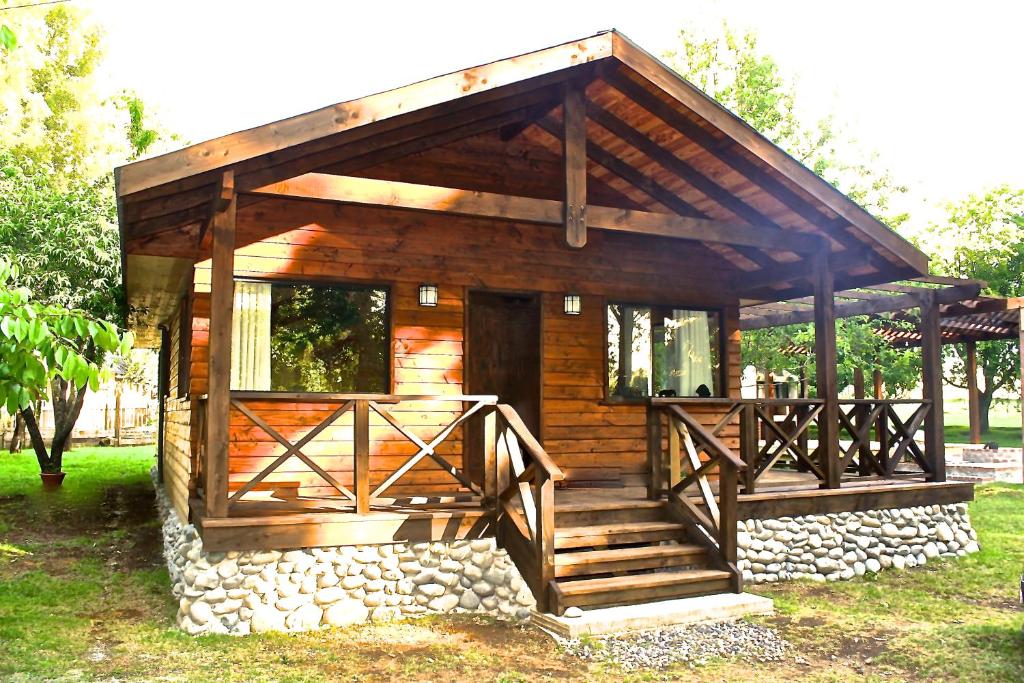 Cabaña de madera con porche y pared de piedra en Cabaña Aroma de Campo, en Villarrica