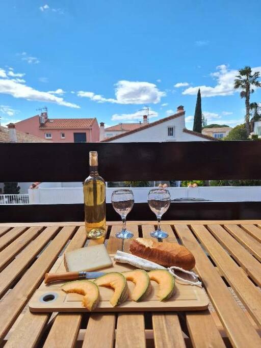 - une table en bois avec 2 verres de vin et du pain dans l'établissement A L AZURA Joli Duplex tout proche plage - Clim Wifi parking - Hameau de la Plage, à Saint-Cyprien