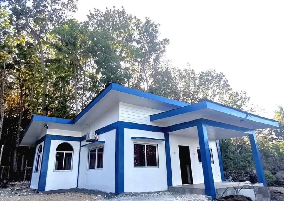a small blue and white house with trees in the background at House with Sunrise&Beach view in Candaping B