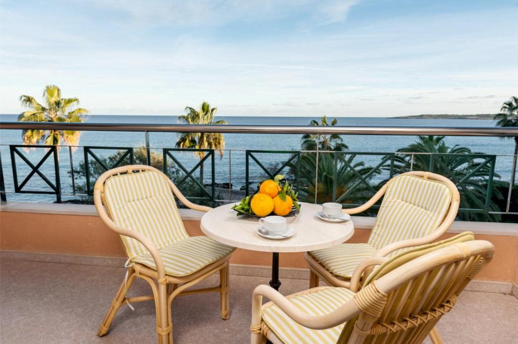 een tafel en stoelen op een balkon met uitzicht op de oceaan bij Apartamentos Xaloc HRC in Cala Millor