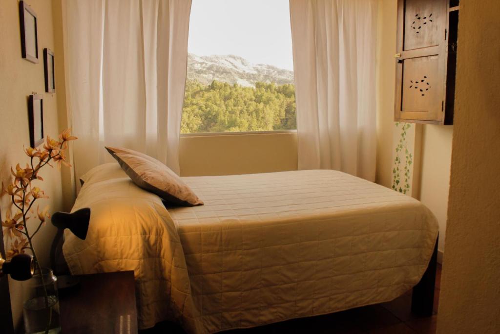 a small bedroom with a bed with a window at Casa Encuentro Ecolodge, Outdoor Gym and Yoga in Guatapé