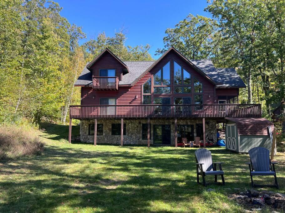 een groot houten huis met twee stoelen in de tuin bij Welcome to Bear's Den Lodge in Round Lake Seaplane Base